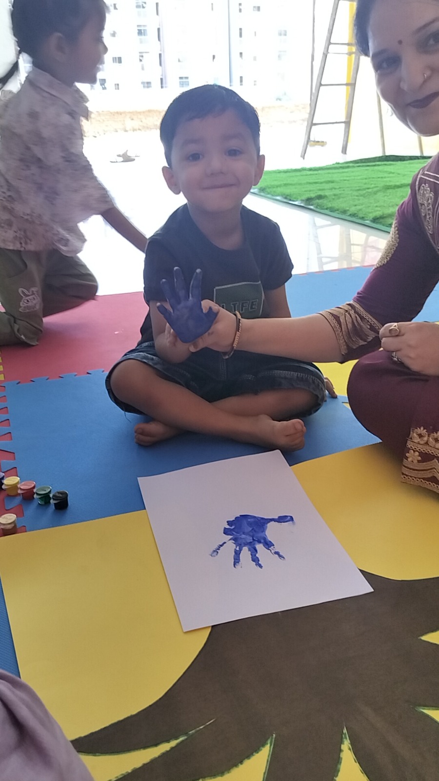 A student at Lily Lotus Preschool Becharaji showing his handprint art